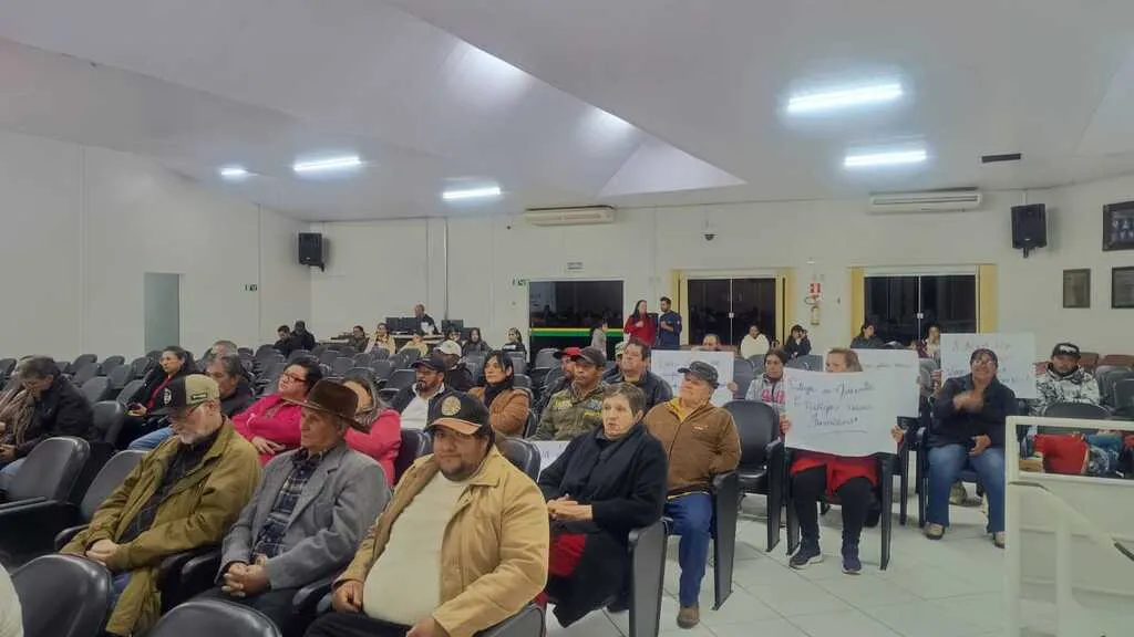 Público sentado no plenário da Câmara Municipal de Pinhão durante sessão, com algumas pessoas segurando cartazes em defesa da água e das nascentes.