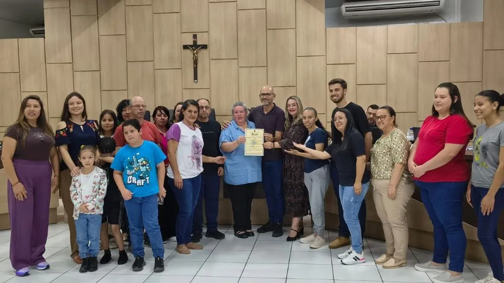 Professora Eolete Aparecida Gomes posa com a Moção de Congratulações ao lado de vereadores, familiares, amigos e integrantes da comunidade surda, durante homenagem realizada na Câmara Municipal de Pinhão.