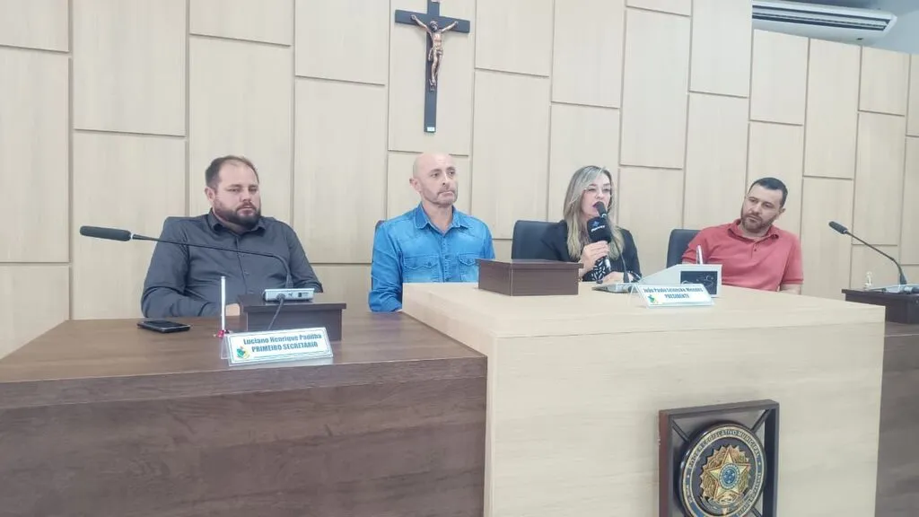 Quatro vereadores sentados à mesa da Câmara Municipal de Pinhão durante coletiva de imprensa. Vilma Kitcky fala ao microfone, acompanhada pelos demais parlamentares.