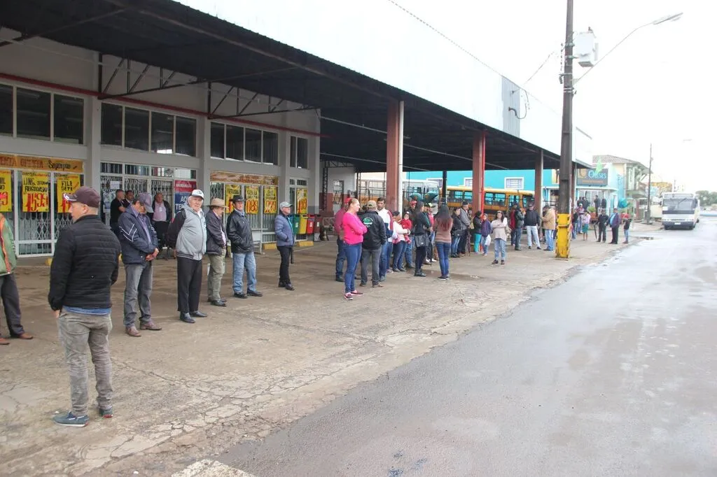 Foto de arquivo das eleições de 2018 mostra pessoas aguardando junto a veículos de transporte no estacionamento do antigo Supermercado Superpão, em Pinhão.